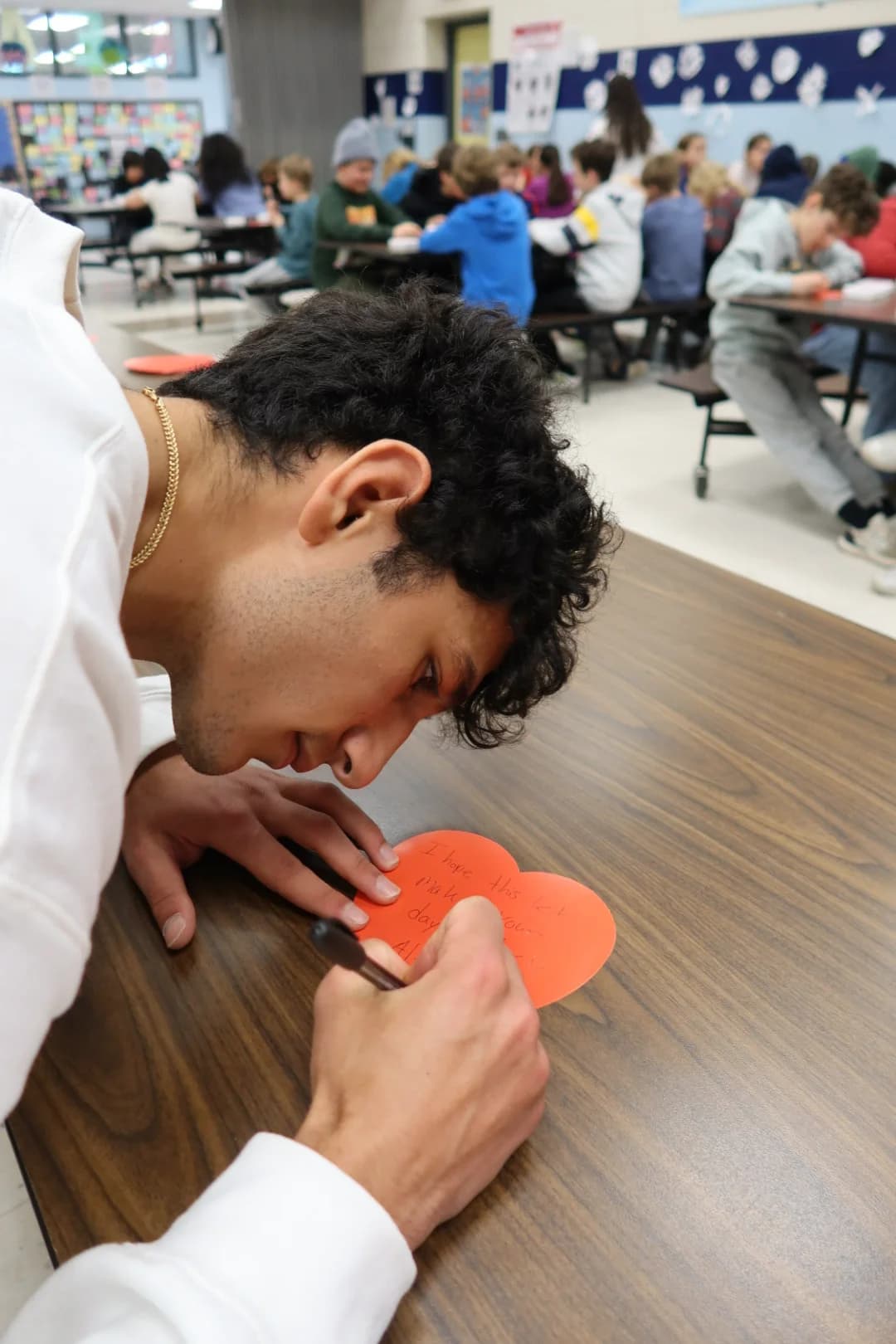 A student writing a personalized heart note for a care kit recipient